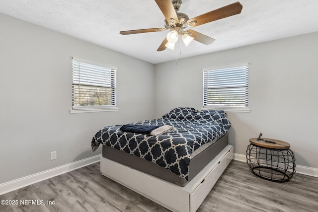 bedroom with multiple windows, a textured ceiling, and wood finished floors