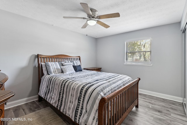 bedroom with baseboards, a textured ceiling, and wood finished floors