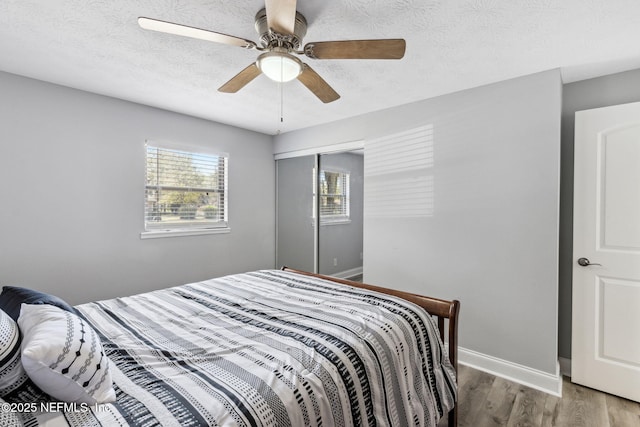 bedroom featuring a closet, baseboards, a textured ceiling, and wood finished floors