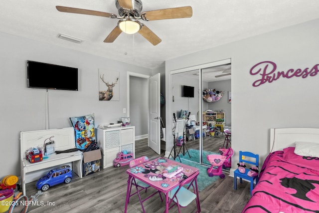 bedroom featuring a ceiling fan, wood finished floors, visible vents, a closet, and a textured ceiling