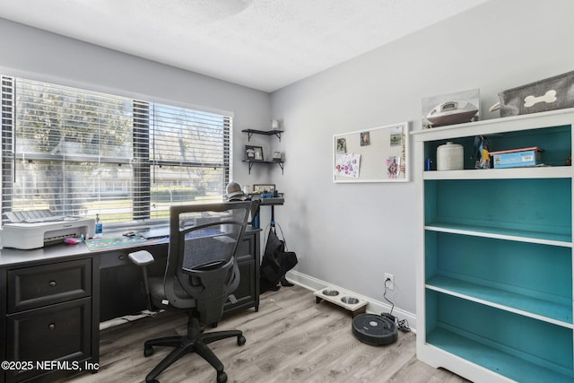 office area with light wood-type flooring, baseboards, and a textured ceiling