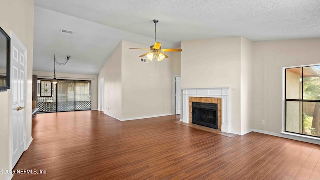 unfurnished living room with a tile fireplace, visible vents, ceiling fan, and wood finished floors