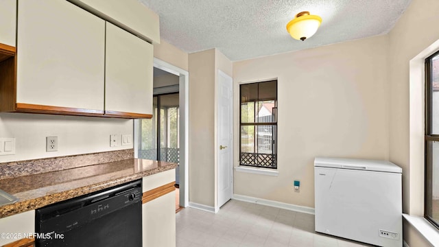 kitchen with black dishwasher, baseboards, dark stone countertops, a textured ceiling, and fridge