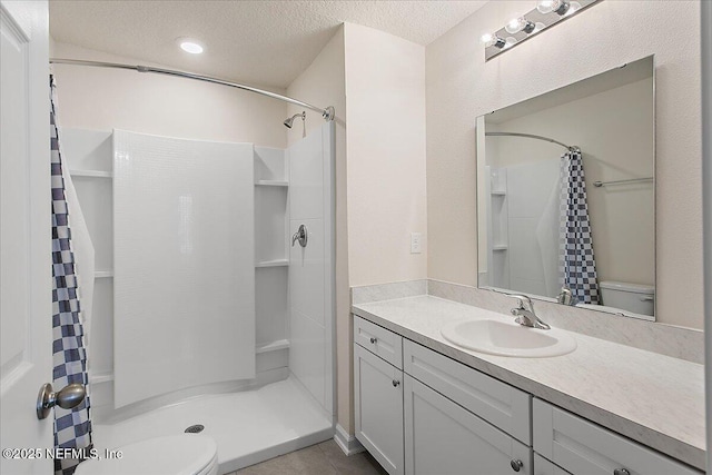 full bath with toilet, a shower stall, a textured ceiling, and vanity