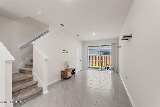 foyer entrance featuring light tile patterned floors, visible vents, stairs, and baseboards