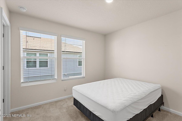 bedroom with carpet, baseboards, and a textured ceiling