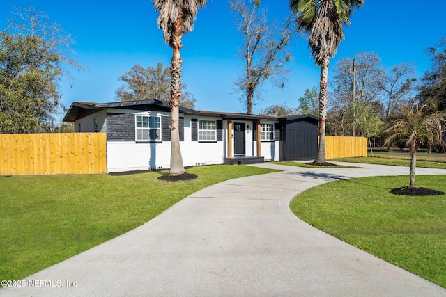 view of front facade featuring concrete driveway, a front yard, and fence