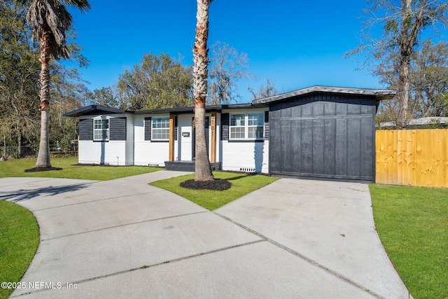 view of front of house featuring concrete driveway, a front lawn, board and batten siding, and fence