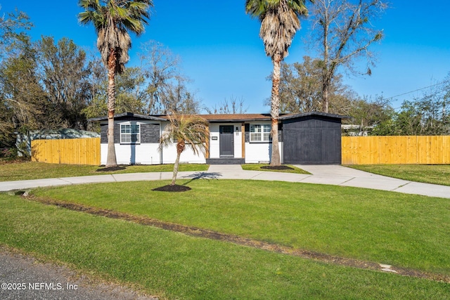 view of front of home with fence, concrete driveway, and a front yard