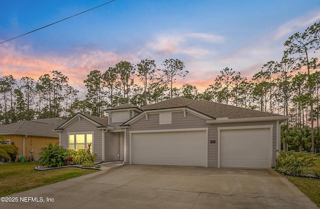 view of front of house featuring a garage, concrete driveway, and a shingled roof