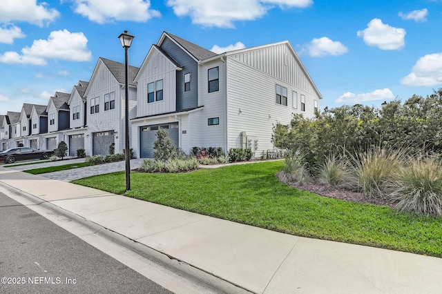 view of front of house with board and batten siding, a front yard, a garage, a residential view, and driveway