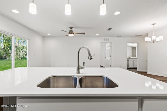 kitchen featuring decorative light fixtures, light countertops, a sink, and visible vents