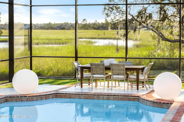 pool featuring glass enclosure, a patio, and a water view