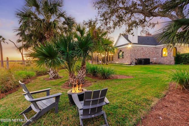 yard at dusk featuring a fire pit and cooling unit