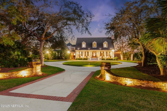 cape cod house with curved driveway and a yard