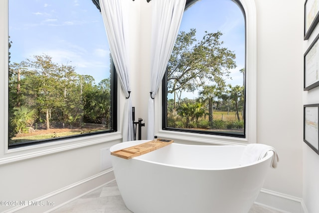 bathroom featuring a soaking tub and baseboards