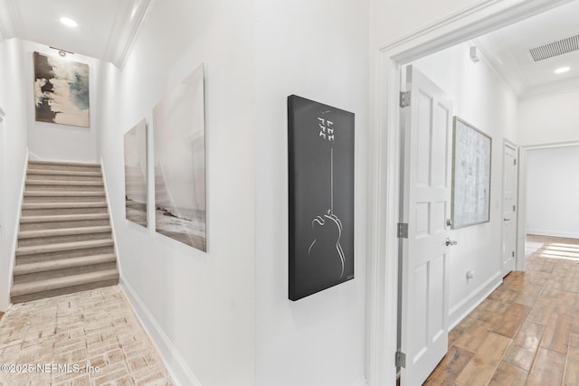 hallway featuring ornamental molding, wood finished floors, visible vents, and baseboards