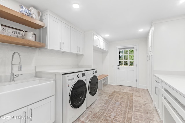 clothes washing area featuring recessed lighting, a sink, baseboards, cabinet space, and washer and clothes dryer