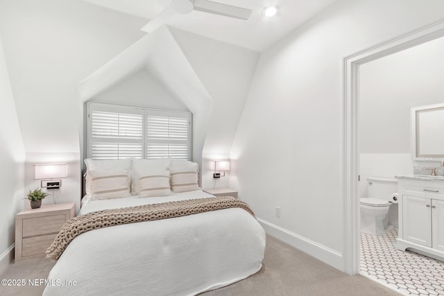 bedroom with baseboards, connected bathroom, light colored carpet, ceiling fan, and vaulted ceiling