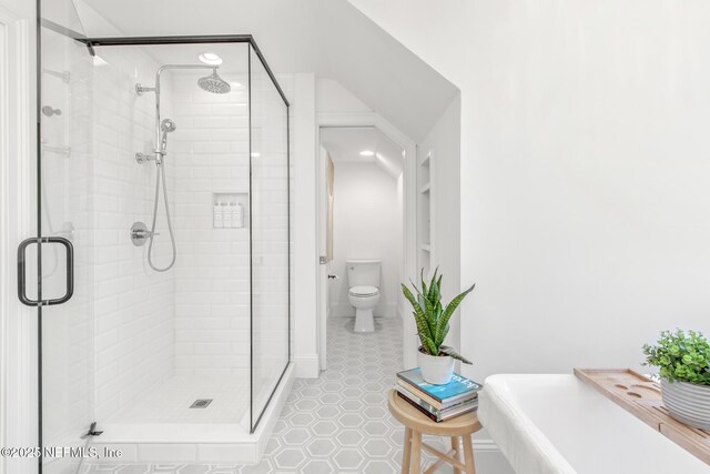 full bathroom featuring toilet, a shower stall, built in shelves, and tile patterned floors