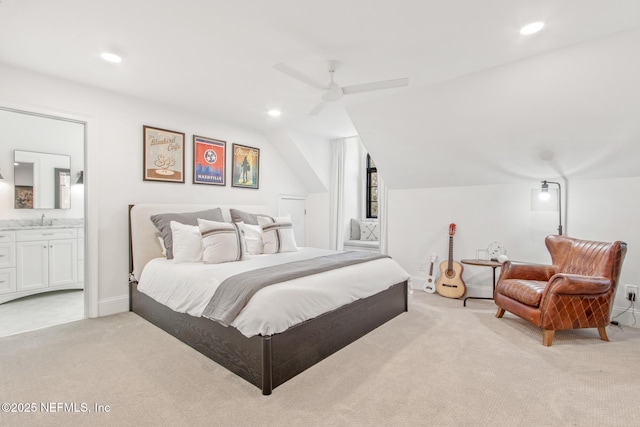 bedroom featuring lofted ceiling, recessed lighting, light carpet, a sink, and ensuite bath