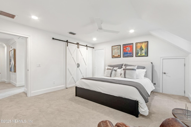 bedroom with a barn door, recessed lighting, visible vents, and light colored carpet