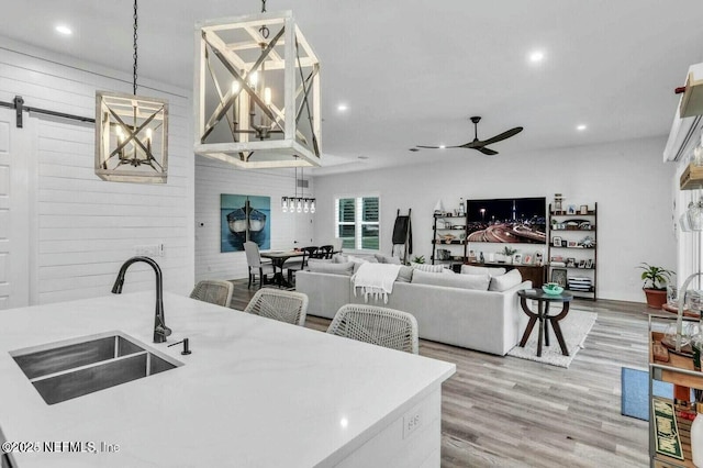 kitchen featuring wood finished floors, a ceiling fan, recessed lighting, a sink, and a barn door