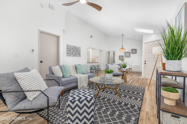 living area with a ceiling fan, a skylight, visible vents, and light wood-style floors