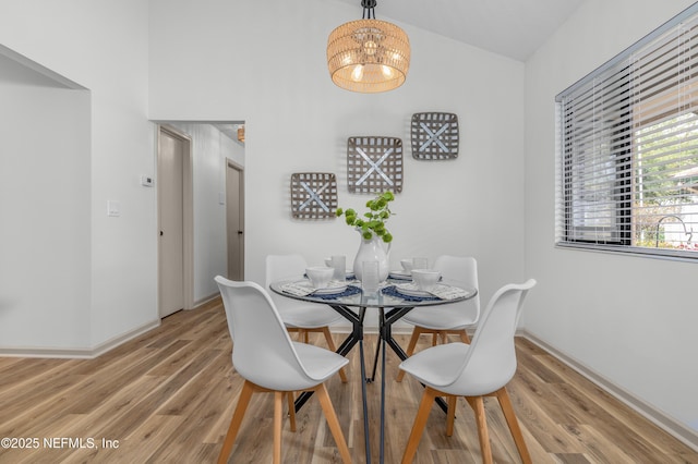 dining space with light wood-type flooring, an inviting chandelier, and baseboards