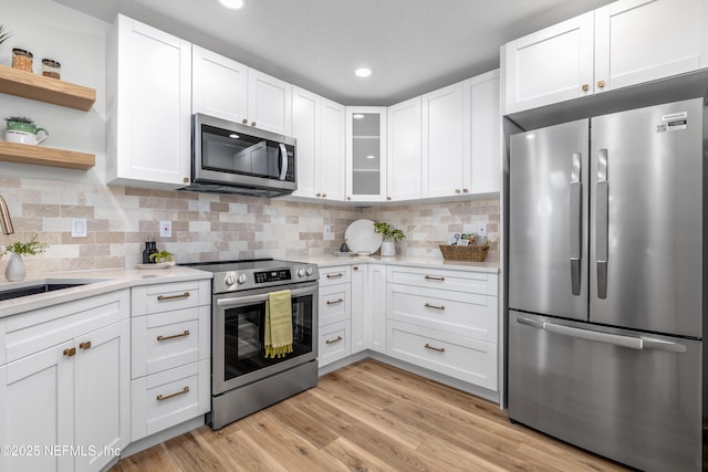 kitchen featuring stainless steel appliances, light countertops, light wood-style flooring, and white cabinetry