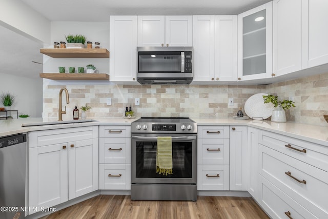 kitchen with appliances with stainless steel finishes, light countertops, white cabinets, and a sink