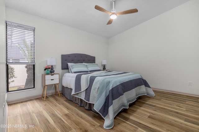 bedroom with a ceiling fan, baseboards, and wood finished floors