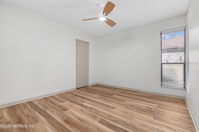 spare room with light wood-style floors, ceiling fan, a textured ceiling, and baseboards