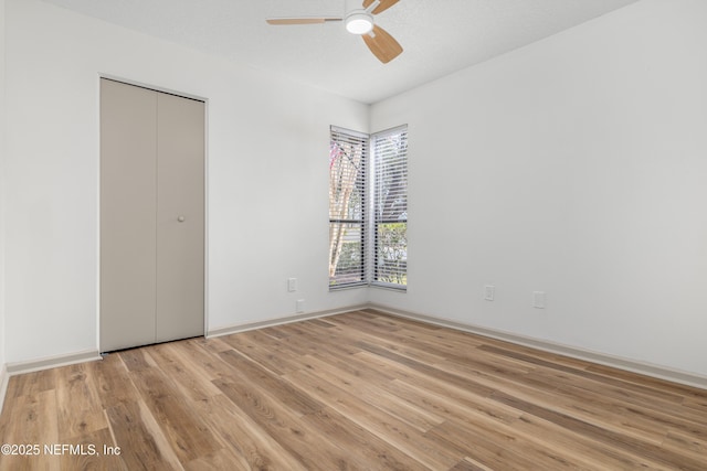 unfurnished bedroom with baseboards, a closet, a ceiling fan, and light wood-style floors