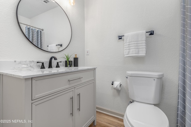 full bath with baseboards, vanity, toilet, and wood finished floors