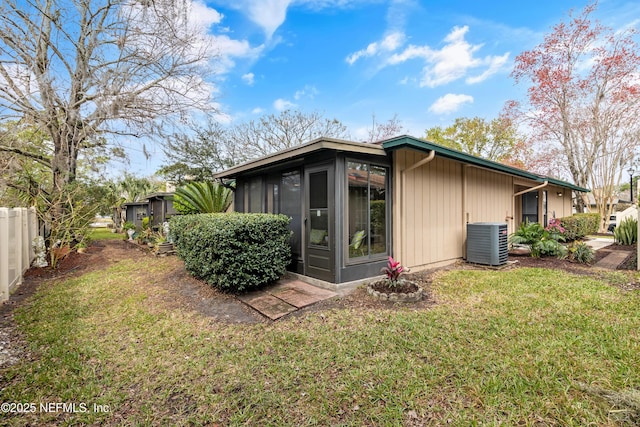 back of property with a sunroom, fence, central AC unit, and a yard