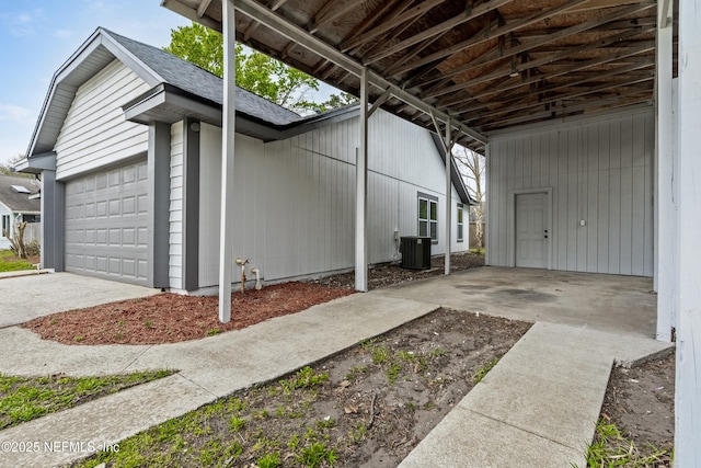 view of home's exterior featuring central AC, concrete driveway, roof with shingles, and an attached garage