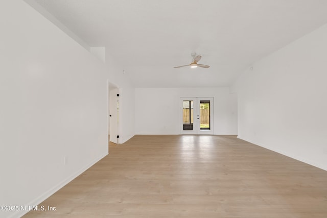 spare room with french doors, light wood finished floors, lofted ceiling, ceiling fan, and baseboards