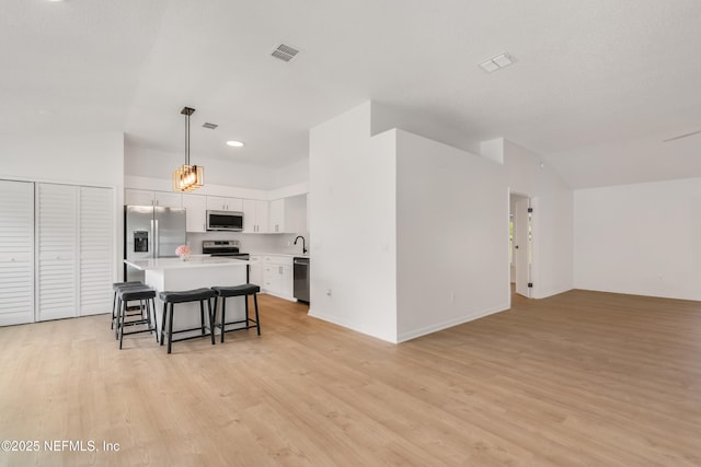 kitchen featuring visible vents, appliances with stainless steel finishes, a center island, light countertops, and white cabinetry