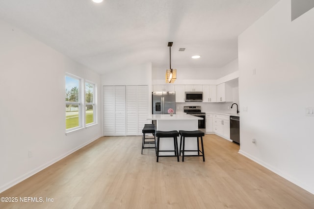 kitchen with stainless steel appliances, a breakfast bar area, light countertops, and light wood-style flooring