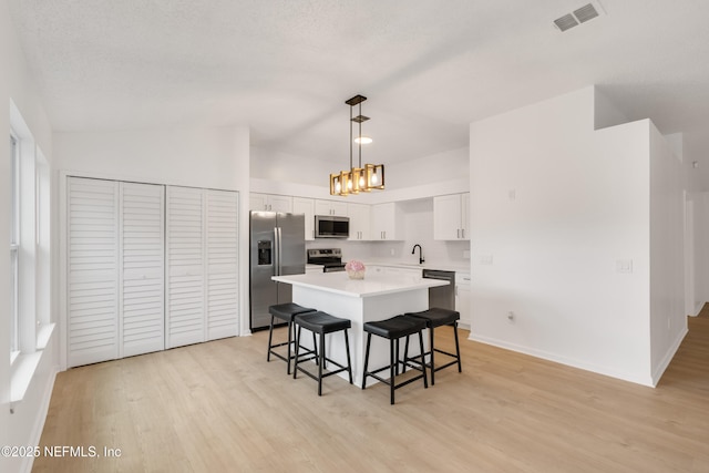 dining area with a textured ceiling, visible vents, baseboards, light wood finished floors, and an inviting chandelier