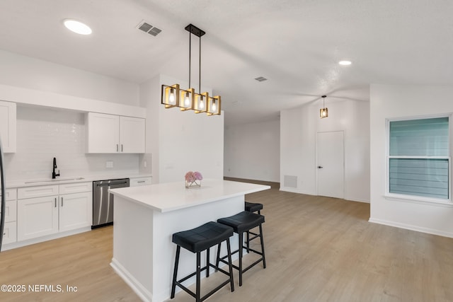 kitchen featuring a sink, visible vents, a kitchen breakfast bar, stainless steel dishwasher, and a center island