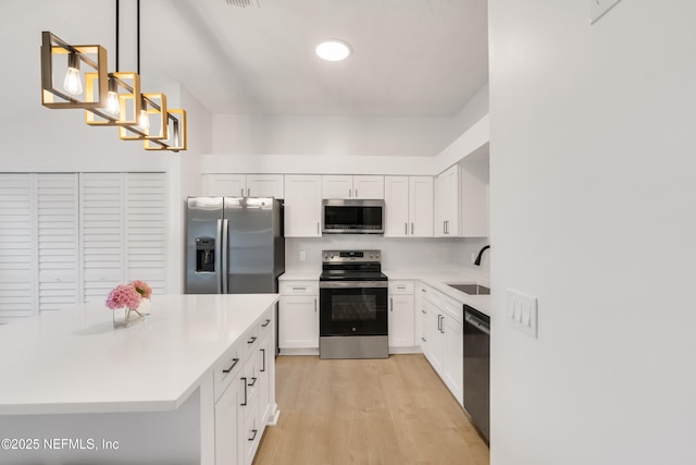 kitchen featuring stainless steel appliances, a sink, light countertops, decorative backsplash, and light wood finished floors