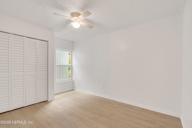 unfurnished bedroom with a textured ceiling, ceiling fan, baseboards, a closet, and light wood finished floors