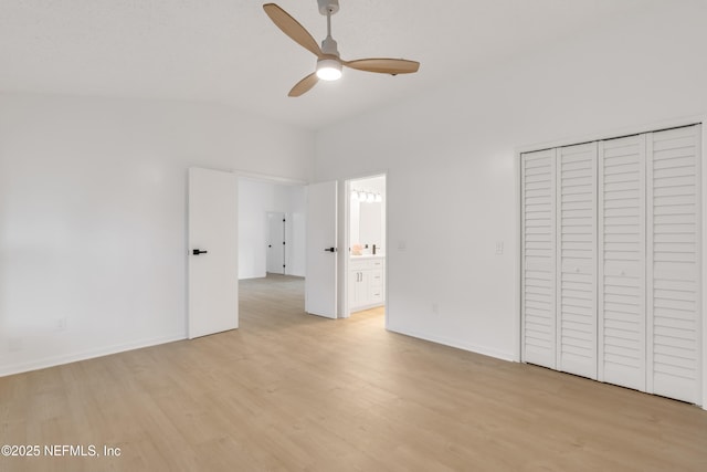 unfurnished bedroom featuring lofted ceiling, light wood-type flooring, ensuite bathroom, and baseboards