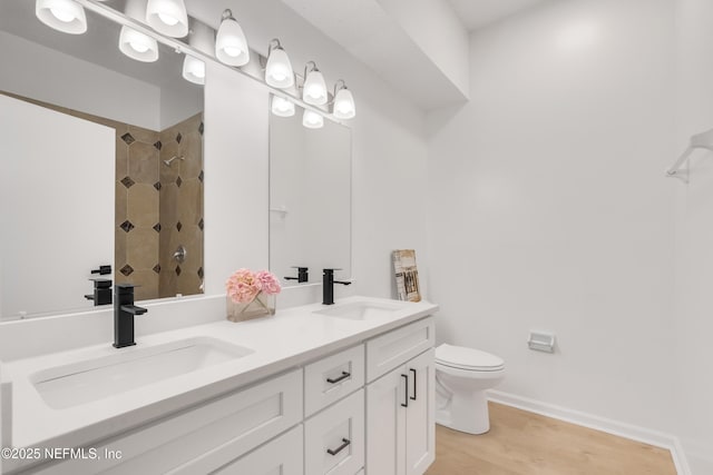 bathroom with double vanity, wood finished floors, a sink, and toilet