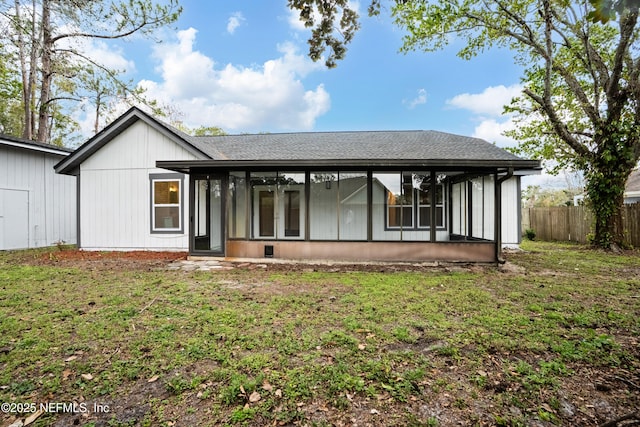 back of house with a sunroom, a shingled roof, fence, and a lawn