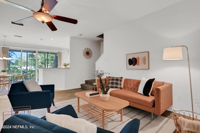 living room featuring recessed lighting, visible vents, stairway, wood finished floors, and ceiling fan with notable chandelier