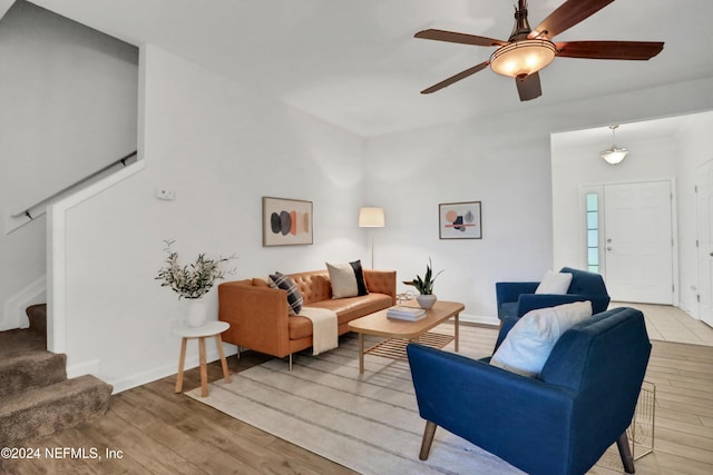 living area featuring light wood-style floors, baseboards, and stairs