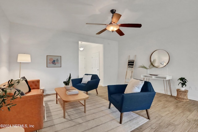 living room featuring ceiling fan, baseboards, and wood finished floors